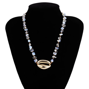 Dettaglio della collana boho con grande conchiglia dorata e perle di opale su supporto nero