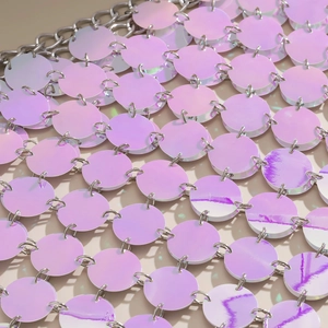 Close-up of iridescent pink and purple sequins linked by metal rings on a body chain