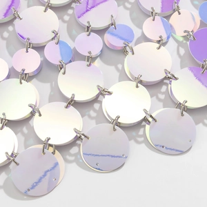 Macro shot of iridescent round sequins connected by silver rings on a sexy body chain