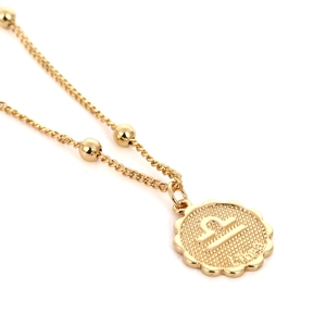 Makroaufnahme einer goldenen Waage Sternzeichenkette mit graviertem Symbol und Text