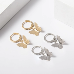 Detail view of gold and silver butterfly charm hoop earrings with fine matte texture