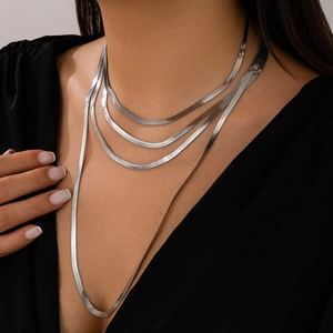 Detailed close-up of layered silver snake chain necklaces on a model with a black V-neck top