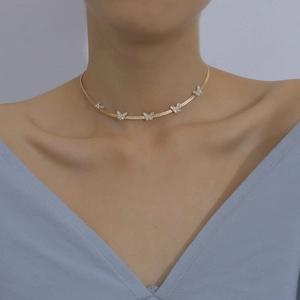 Close-up of a gold butterfly choker necklace with sparkling stones on a model's neck