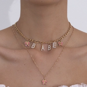 Close-up of gold layered necklace with pink rhinestone butterflies and BABE letter pendant