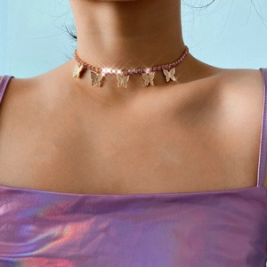Detail shot of golden butterfly choker necklace featuring pink rhinestones on a female model