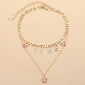 Close-up of golden double-layer necklace with pink crystal butterflies and BABE pendant