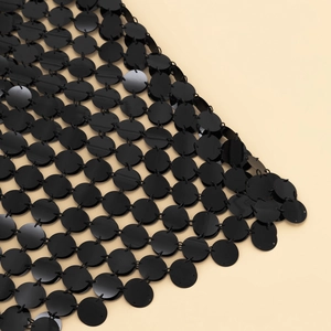 Détail de paillettes noires reliées par des anneaux pour une structure en maille souple