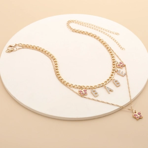 Detail of gold babe letter pendant and pink crystal butterfly on double layered necklace