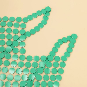 Détail d'un sac à main à paillettes vertes avec anneaux métalliques et fini brillant