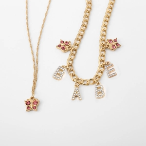 Detail of gold Cuban chain with pink crystal butterflies and BABE letter pendants