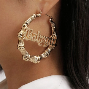 Nahaufnahme der goldenen Ohrringe mit Bambustextur und dem babygirl-Schriftzug-Design