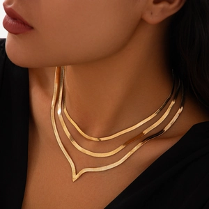Detail of layered gold snake chain necklaces with V-shaped geometric pendant on model