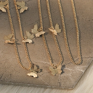 Macro detail of golden butterfly pendant chain with intricate hollowed texture