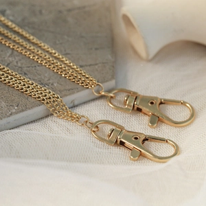 Detail of golden metal chain with lobster clasps and fine links in punk hip-hop style