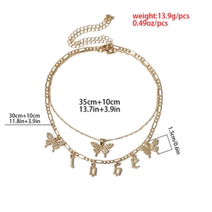 Detail of double-layer gold butterfly necklace with Figaro chain and LOVE charms