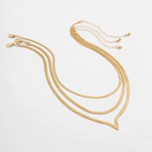 Detail of three-piece gold snake bone chains with lobster clasps and extension links