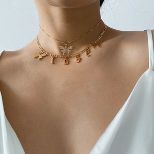 Model wearing a layered gold butterfly necklace with crystal accents and LOVE pendant
