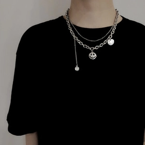 Detail of silver double-layered chain necklace featuring pendant smiley faces on o-link