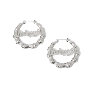 Nahaufnahme der Bambus-Ohrringe mit silbernem Babygirl-Schriftzug im Gothic-Stil