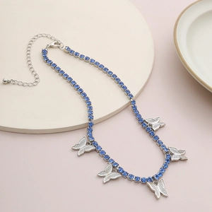 Detailed close-up of a silver butterfly necklace with blue crystals on a display stand