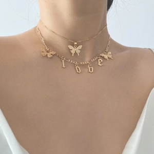 Detail of layered gold butterfly necklace with Love letter charms on a model's neck