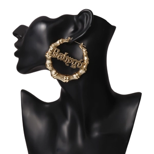 Details von goldfarbenen Bambus-Creolen mit gotischem Babygirl-Schriftzug für Damen