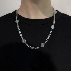 Detail of silver chain necklace featuring round charms with smile and sad face emojis