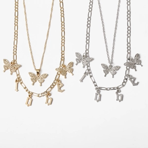 Detail of gold and silver layered butterfly necklaces with dainty chain and LOVE pendants