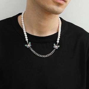 Detail of a pearl and silver chain necklace with iridescent butterfly charms on a model