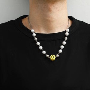 Detail of beaded necklace featuring white pearls, silver beads and yellow smiley face charm