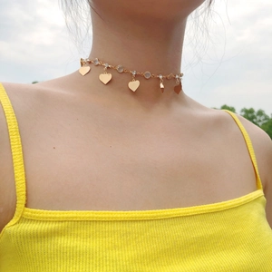 Collana girocollo dorata con ciondoli a cuore e strass indossata da una modella all'aperto