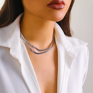 Detail of a silver double-layered snake bone chain necklace worn with a white shirt