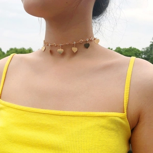 Dettaglio della collana girocollo dorata con ciondoli a cuore e strass su una modella