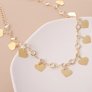 Dettaglio della collana a catena dorata con ciondoli a cuore e strass rotondi lucidi