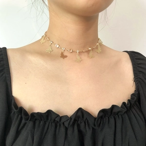 Dettaglio di una collana girocollo a farfalla dorata con ciondoli traforati e zirconi