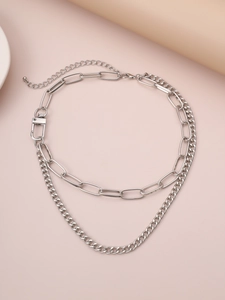 Detail of layered silver chain necklace featuring bold oval links and thin Cuban style