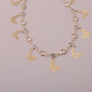Dettaglio della collana dorata con ciondoli a farfalla traforati e strass lucenti