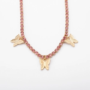 Detailed view of gold butterfly necklace with light pink rhinestones on white background