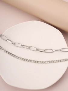 Close-up of layered silver chain necklace with rectangular links on aesthetic display