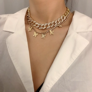Primer plano de collar doble dorado con cadena cubana y cinco dijes de mariposa con brillo