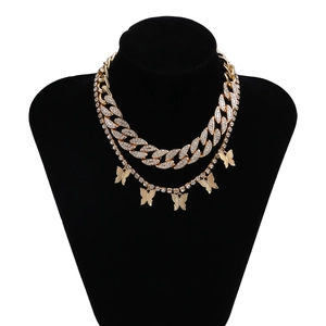 Detalle de cadena cubana dorada y collar de tenis con dijes de mariposas de pedrería