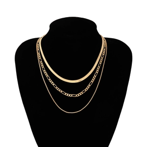 Detailed view of triple-layered golden snake and figaro chain necklace on a black bust