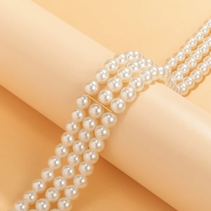 Detalle de collar de perlas de tres capas con espaciadores dorados en diseño paralelo