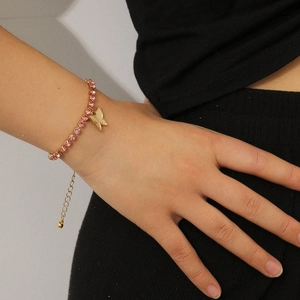 Close-up of a pink rhinestone bracelet with a golden butterfly pendant and adjustable chain