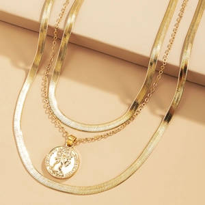 Detailed view of layered gold snake chains and coin pendant with embossed portrait