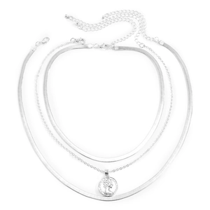 Close-up of triple-layered silver snake chains with a vintage coin pendant necklace
