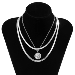 Detailed view of triple-layered silver snake chains with engraved coin pendant