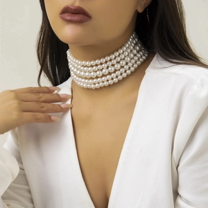 Primer plano de collar de perlas de cinco capas en modelo con elegante top blanco en V