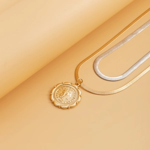 Detail of mixed gold and silver snake chain necklace featuring a vintage 1988 coin pendant