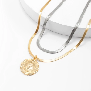 Close-up of gold and silver herringbone snake chains with an Italian coin pendant